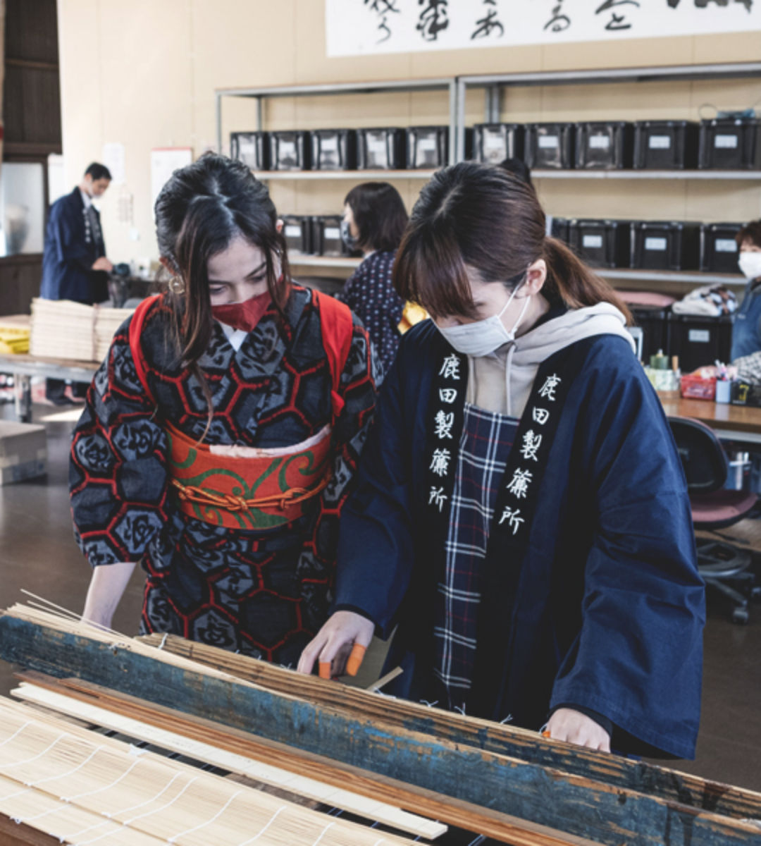 写真:製造する織元を見学し、実際に触ってみたりしている様子。